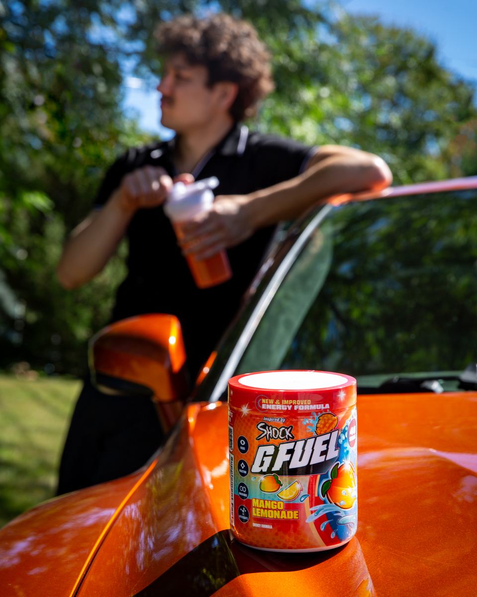 Shock leaning on his orange car with a Mango Lemonade tub on the hood