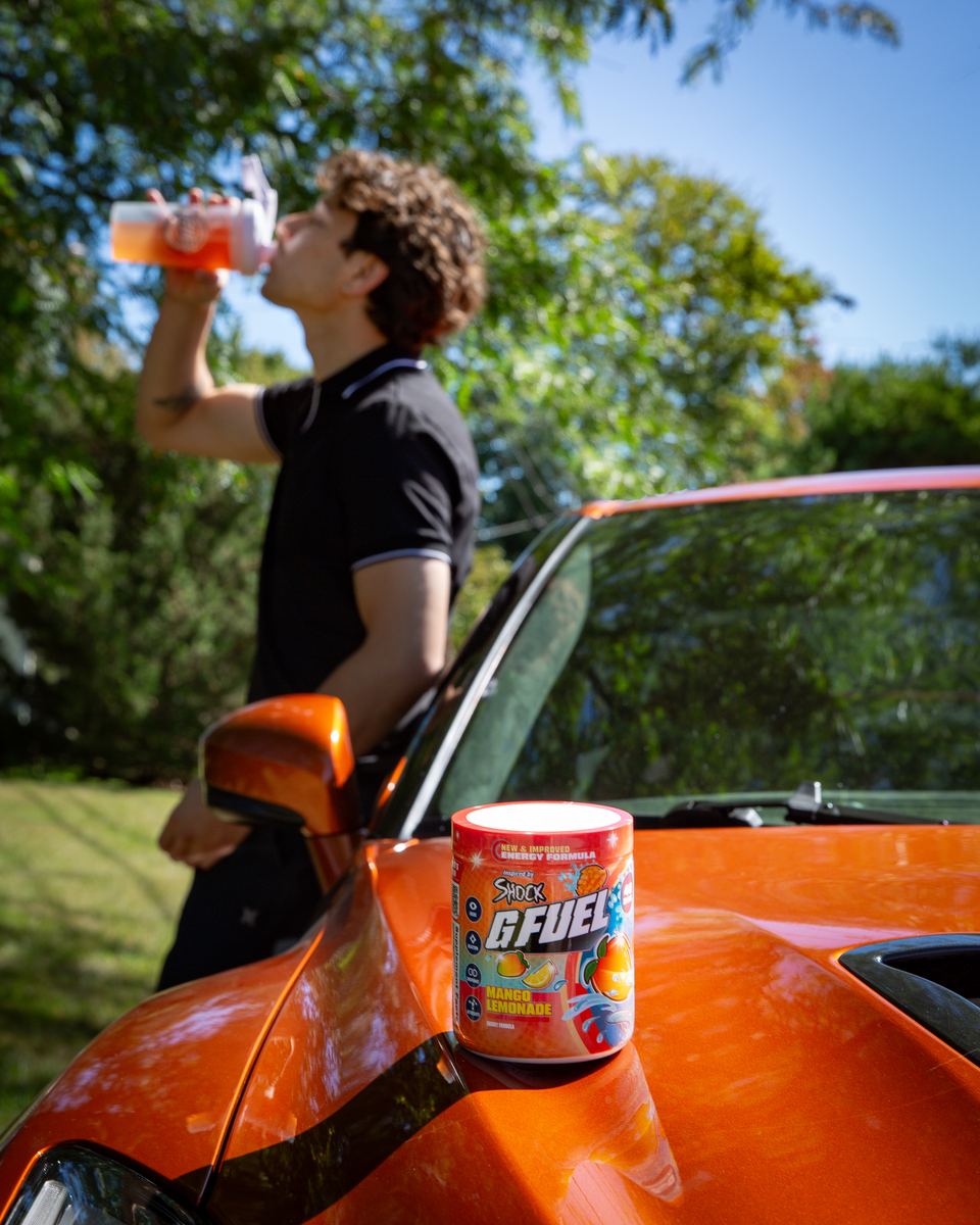 Shock drinking Mango Lemonade from a G FUEL shaker beside his car